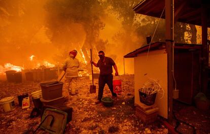 Morador carrega balde de água enquanto luta para salvar sua casa do incêndio de Ranch Long New Valley Road, perto de Clearlake Oaks, Califórnia, em 4 de agosto de 2018.