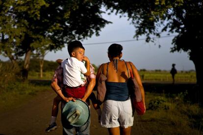 Un padre lleva a su hijo a hombros a la escuela, a lo largo de la carretera, donde se encuentra la casa museo de los Hermanos Castro en Birán (Cuba).