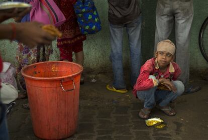 Un niño sin hogar se alimenta de comida distribuida por organizaciones no gubernamentales fuera de un hospital en Nueva Delhi, India.