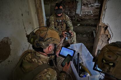 Several members of the unit follow the flight of a kamikaze drone above enemy trenches. 