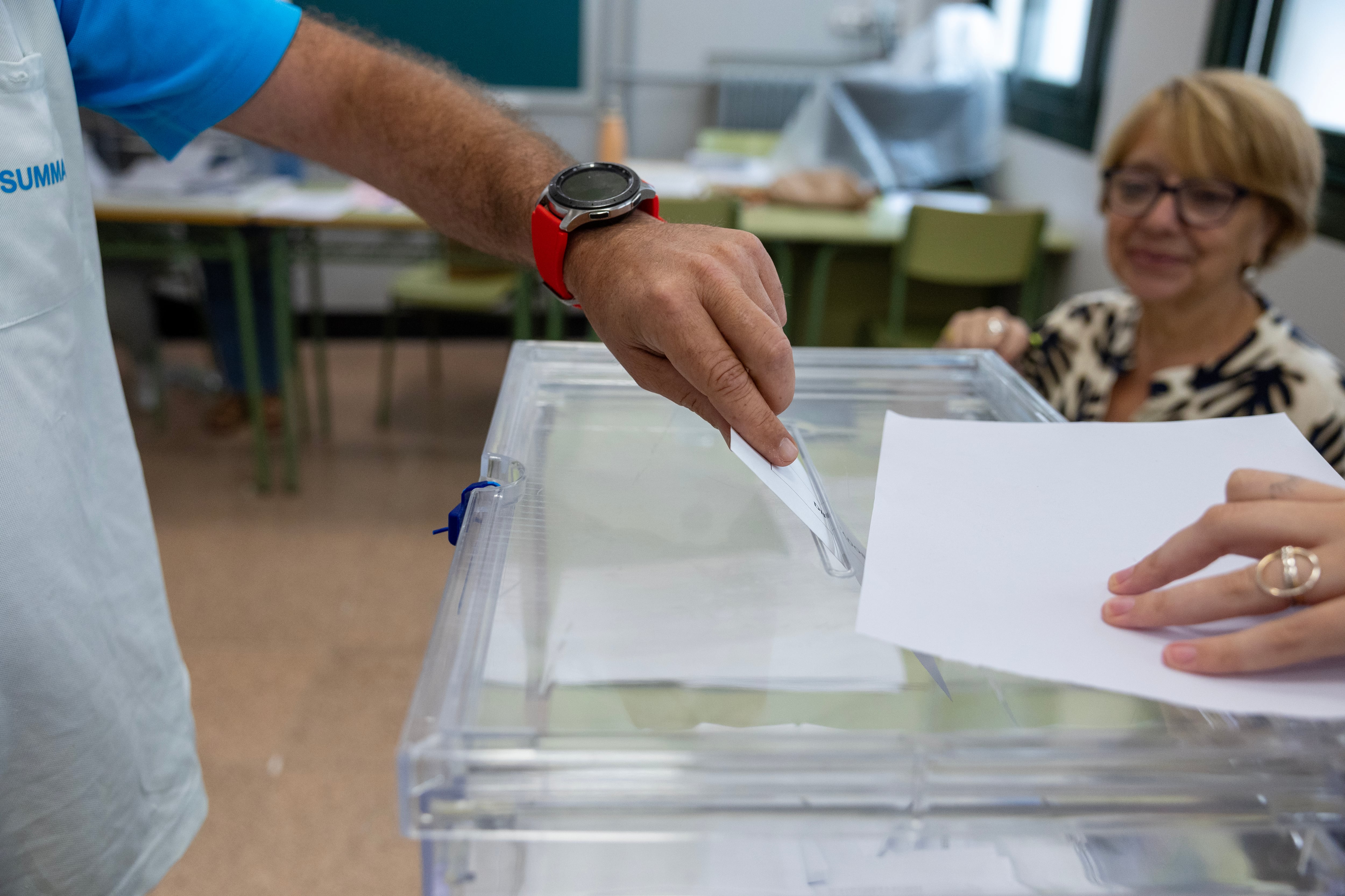 Un hombre introduce su voto en la urna de un colegio electoral en Madrid. 