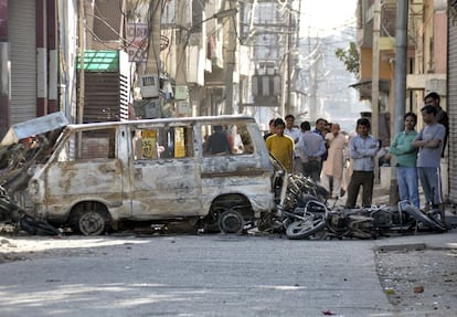 Varias personas observan veh&iacute;culos quemados durante la protesta de la casta jat en el estado de Haryana, India, el 21 de febrero.