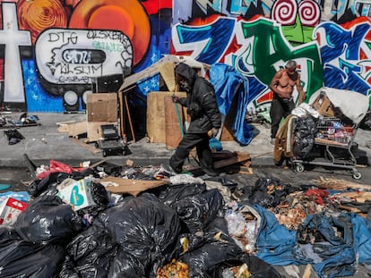 Dos hombres rebuscan entre la basura en una calle de Los Ángeles.