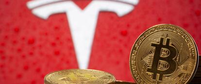 Representanción de la moneda virtual bitcóin, delante del logo de Tesla.