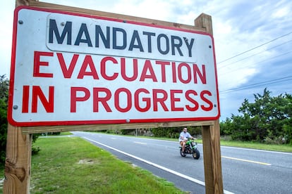 A person rides a bike near a 'mandatory evacuation' sign, as the town prepares for Hurricane Idalia, in Cedar Key, Florida, USA, 29 August 2023.