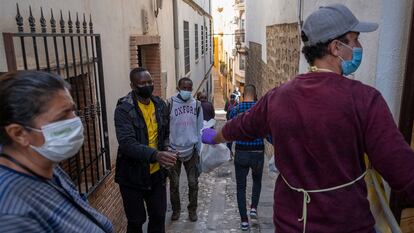 Un grupo de temporeros recoge una bolsa con alimentos, en la sede de Cáritas de Jaén.