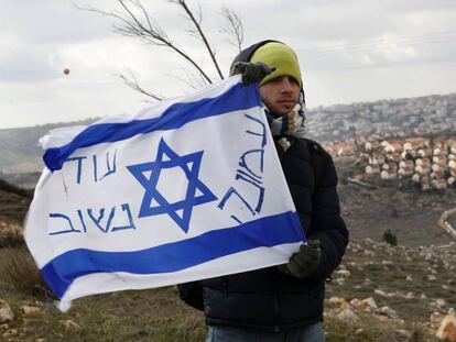 Un colono jud&iacute;o con una bandera isarel&iacute; en el asentamiento de Amona en Cisjordania.