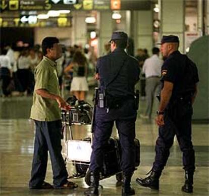 Un policía charla con un pasajero en Barajas.