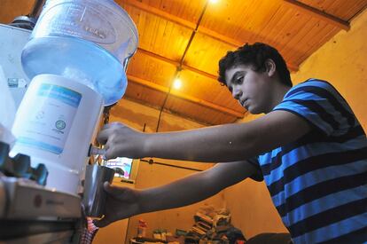 Daniel, hijo de Claudia, llena un vaso de agua de uno de los bidones gratuitos que facilita la Autoridad de la Cuenca Matanza-Riachuelo a los habitantes de Villa Inflamable. “El agua de la canilla —el grifo— a veces sale limpia, pero otras veces sale toda verde”, comenta una vecina.