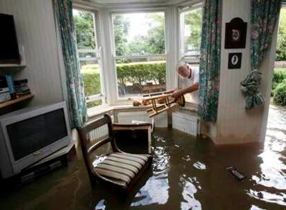 Un vecino de Tewkesbury (centro de Inglaterra) rescata los muebles de su casa, inundada por las lluvias del fin de semana.