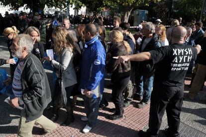 Los griegos que han acudido a este reparto hacen cola para recoger su bolsa con alimentos repartidos por los neonazis de Amanecer Dorado.