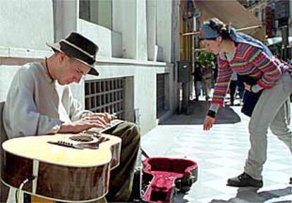 Eric Mongrain, en plena calle, tocando su guitarra acústica de una forma peculiar.