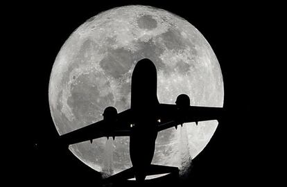 Un avión de pasajeros en ruta hacia el aeropuerto de Los Ángeles pasa por delante de una luna llena, a la altura de Whittier (California).