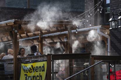 Unos aspersores refrescan a los comensales de un restaurante en Seattle durante el día más caluroso jamás registrado en la ciudad. Las redes eléctricas del país se preparan para la contingencia de un exceso de consumo que sobrepasase su capacidad.