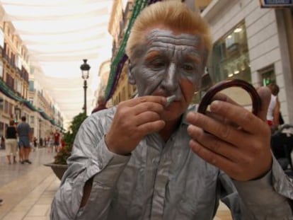 Un mimo se maquilla para actuar en la calle Larios de M&aacute;laga.