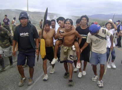 Unos indígenas trasladan a un herido tras un enfrentamiento.