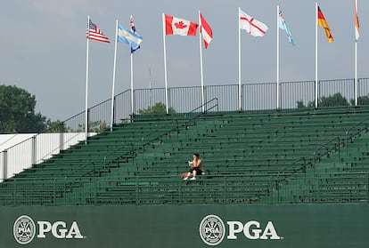 Una mujer lee un libro en las gradas vacías del green 18 mientras antes de la segunda ronda de práctica para el 90º Campeonato de la PGA, el 5 de agosto de 2008 en Bloomfield Township, Michigan.