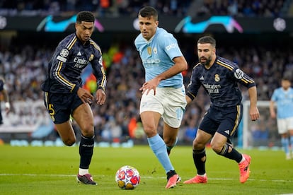 Rodri conduce el balón entre Bellingham y Carvajal.
