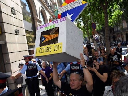 Un hombre sostiene una urna de cartón con una estelada frente al Tribunal Superior de Justicia de Barcelona.