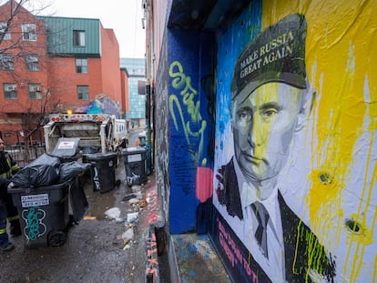 Un hombre recoge la basura de un callejón de Toronto ante un retrato de Vladímir Putin, este lunes.