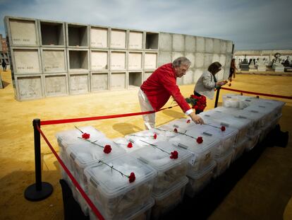 Familiares de víctimas dejan claveles sobre las cajas con restos de represaliados antes de ser depositados en el columbario-memorial de Pico Reja, que se inauguró el pasado lunes en el cementerio sevillano.