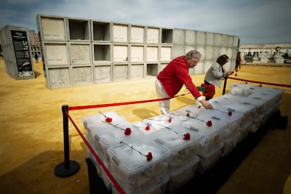 Familiares de víctimas dejan claveles sobre las cajas con restos de represaliados antes de ser depositados en el columbario-memorial de Pico Reja que se inauguró en abril en el cementerio sevillano de San Fernando.