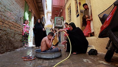 Una mujer refresca a sus hijos en julio pasado en Bagdad.