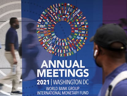 Un hombre pasa por un cartel de las reuniones anuales del Grupo del Banco Mundial y el Fondo Monetario Internacional, el 11 de octubre de 2021 en Washington.