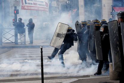 El gas lacrimógeno flota alrededor de la policía antidisturbios durante los enfrentamientos en la tradicional marcha sindical del 1 de mayo en París.