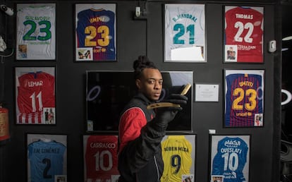 Archibardo Hernández 'Wizarchy', con la navaja en su peluquería de La Latina. De fondo, las camisetas de varios futbolistas que pasaron por allí.