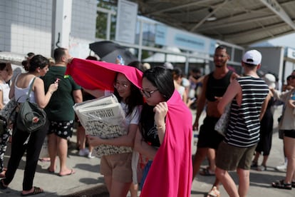 Dos mujeres se protegen con una tela del calor mientras esperan para entrar en el concierto de Taylor Swift en Río de Janeiro, el viernes 17 de noviembre.