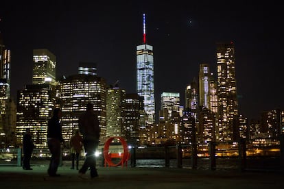 Uns vianants observen des de la distància The One World Trade Center, l'edifici més alt de la zona aquest de Nova York (EUA), il·luminat amb els colors de França en solidaritat amb les víctimes dels atemptats perpetrats.