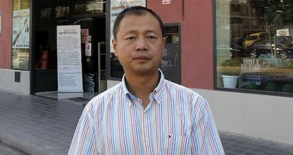 Yi Hu Wang Ji in front of one his shops, with adverts for electronic cigarettes by the doors.