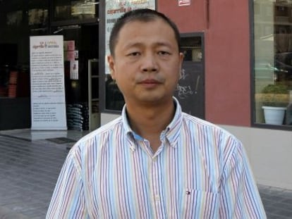 Yi Hu Wang Ji in front of one his shops, with adverts for electronic cigarettes by the doors.