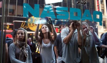 Un grupo de curiosos miran a trav&eacute;s de los cristales del Nasdaq en el d&iacute;a del estreno. 