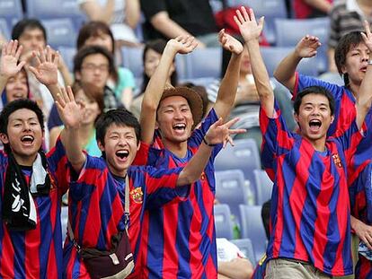 Jóvenes vestidos con la camiseta azulgrana apoyan al Barcelona durante su partido en Yokohama.
