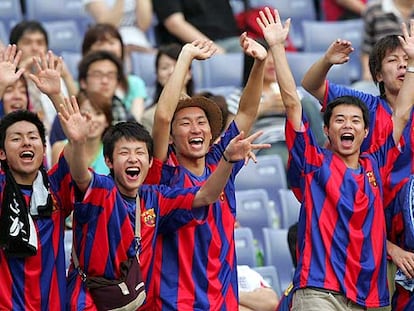 Jóvenes vestidos con la camiseta azulgrana apoyan al Barcelona durante su partido en Yokohama.