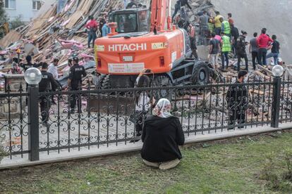 Una mujer reza frente a un edificio destrozado por el terremoto, en Esmirna (Turquía).