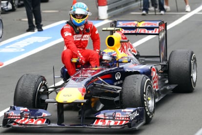 Fernando Alonso, whose Ferrari ran out of petrol after crossing the finish line in second place, is helped by Marc Webber, who finished third