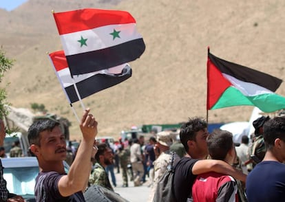 Varios refugiados sirios ondean banderas tras conseguir cruzar la frontera entre Siria y El Líbano, el 28 de junio.