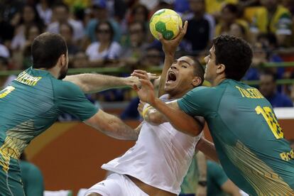 Los brasile?os Jose Guilherme De Toledo (i) y Henrique Teixeira (d), detienen al francs Daniel Narcisse durante los cuartos de final de handbol. 