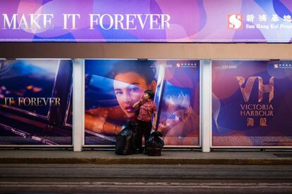 Mujer delante de un panel publicitario en Hong Kong. 