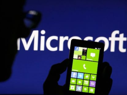 Un hombre con su Nokia Lumia, ante un cartel de Microsoft.