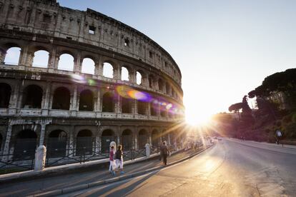 El sol se pone ante el Coliseo de Roma y los visitantes que pasean en torno al monumento.