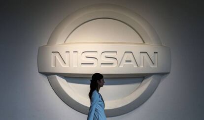 Una mujer camina frente al logo de Nissan en Yokohama.(Japón).