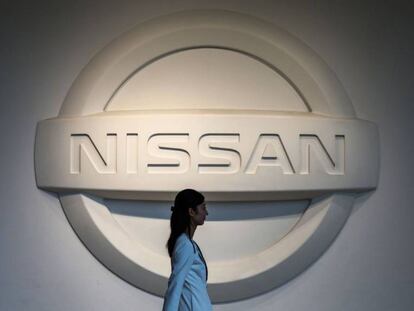Una mujer camina frente al logo de Nissan en Yokohama.(Japón).