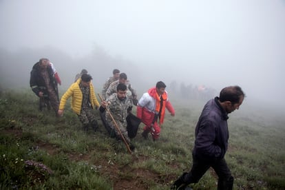 In this photo provided by Moj news agency, rescue team members carry the body of a victim after a helicopter carrying Iranian President Ebrahim Raisi crashed in Varzaqan, northwest Iran. 