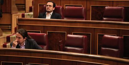 Alberto Garzón y Pablo Iglesias, delante de él, permanecen sentados en sus respectivos escaños.