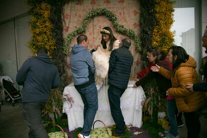 Los familiares de una de las Mayas le ayudan a colocarse en el altar donde pasará horas en la misma posición hasta la ofrenda de flores en la Basílica de Nuestra Señora de los Remedios de Colmenar Viejo. 