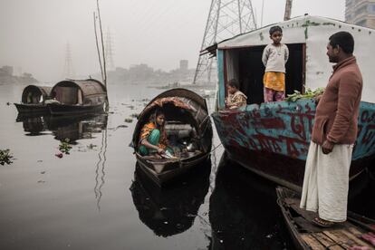 Una mujer cocina, rodeada de su familia, en el bote donde viven sobre el río Buriganga, en Daca. Más de cuatro millones de personas en Dhaka estás expuestas diariamente a las consecuencia de la grave polución del agua.